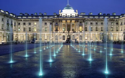 Kensington Palace in London, England, illuminated at night with modern water fountains in the courtyard, captured in an HD desktop wallpaper.