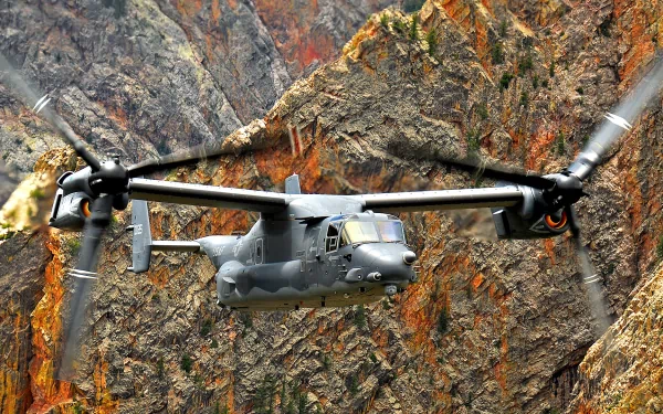 HD desktop wallpaper featuring a Bell Boeing V-22 Osprey military aircraft flying in front of rugged, rocky mountainous terrain.