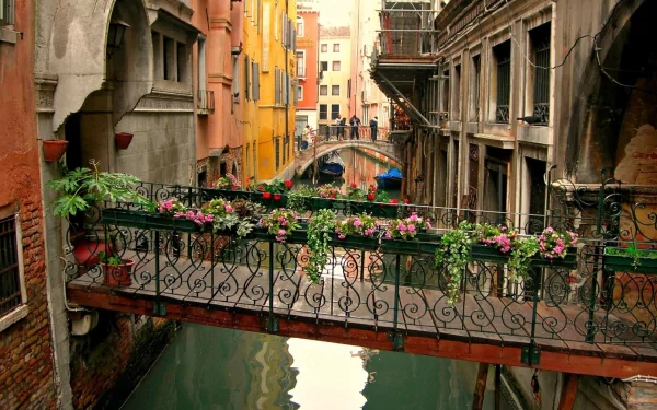 A vibrant scene in Venice featuring colorful buildings, a flower-adorned bridge, and a serene canal, captured in HD for a stunning desktop wallpaper.