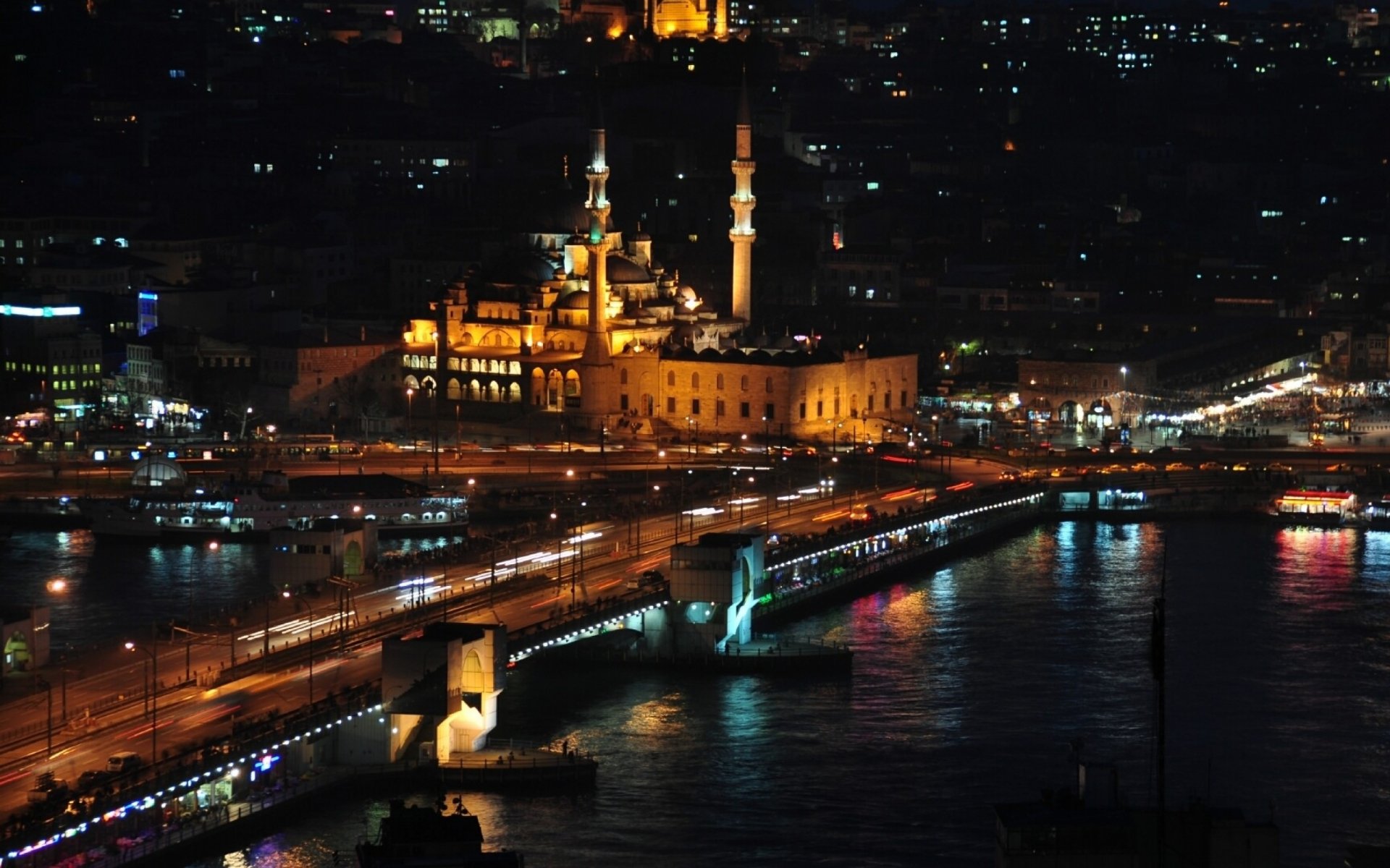 A stunning nighttime view of Istanbul, featuring illuminated buildings and a bustling bridge over the water, capturing the vibrant energy of the city in this HD desktop wallpaper.