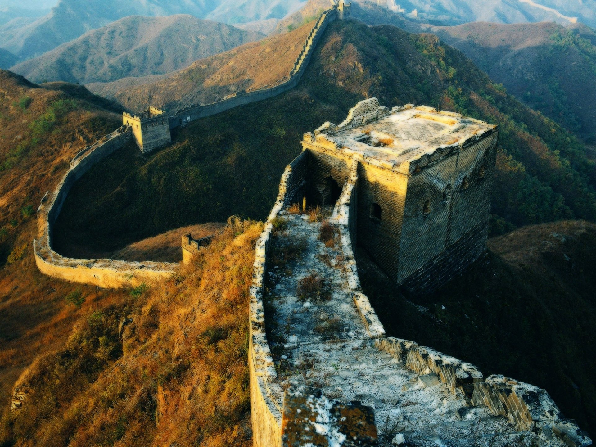 HD desktop wallpaper showcasing the man-made Great Wall of China winding over the mountainous landscape at sunset.