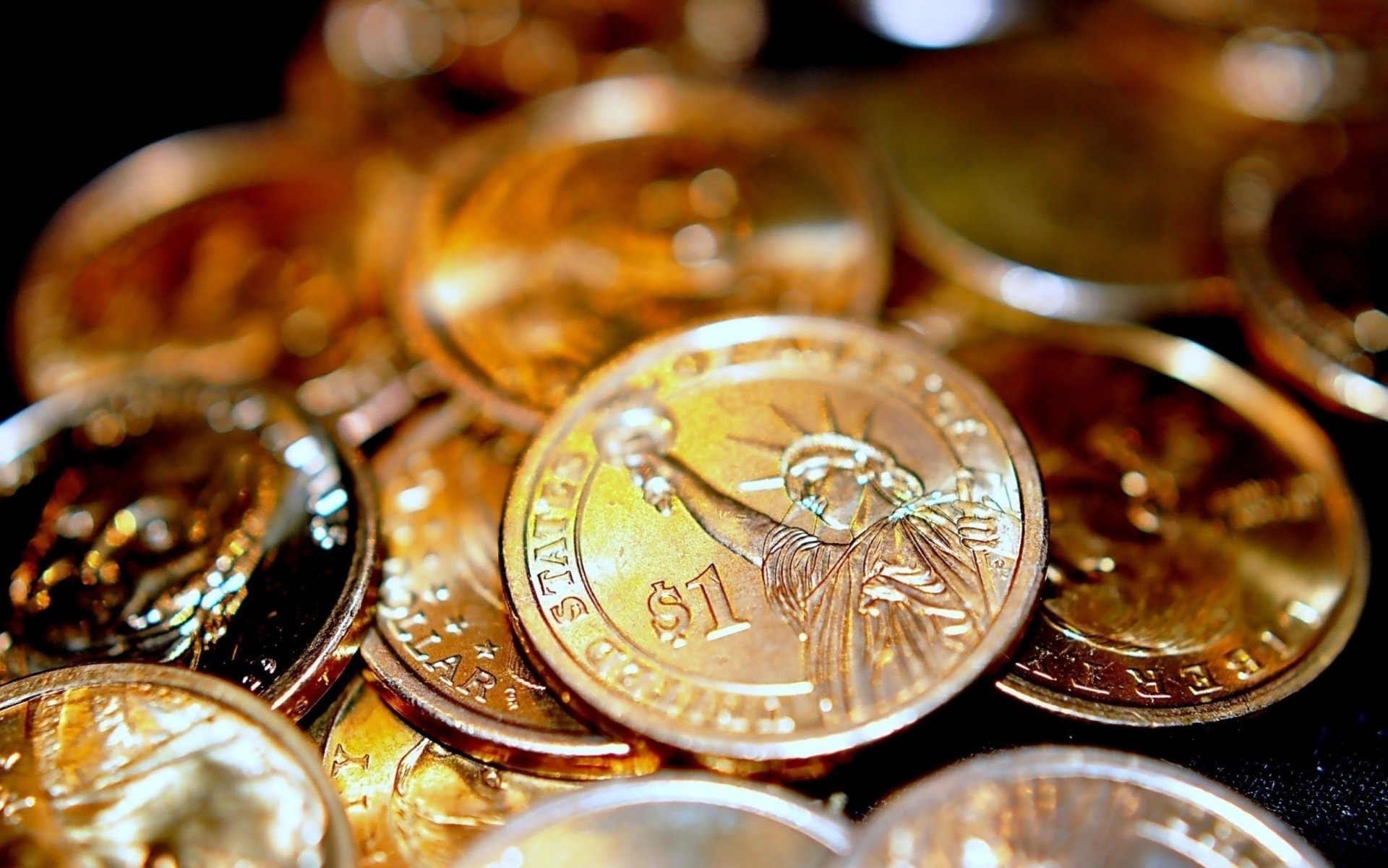 Close-up HD desktop wallpaper showcasing a pile of man-made $1 coins with the Statue of Liberty design, emphasizing rich gold and copper tones.