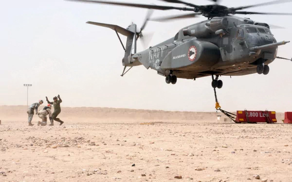 Navy Sikorsky MH-53E Sea Dragon helicopter lifting equipment in a desert, with personnel nearby, showcased in an HD military aircraft wallpaper.