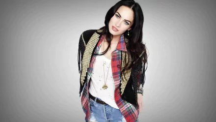Megan Fox poses confidently in a stylish outfit with a layered look, featuring a plaid shirt and denim. This HD desktop wallpaper showcases her striking features against a neutral background.