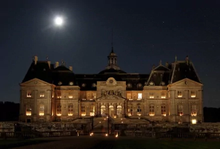 Night view of the illuminated Château de Vaux-le-Vicomte, showcasing its grand architecture under the moonlight in a HD PC desktop wallpaper and background.
