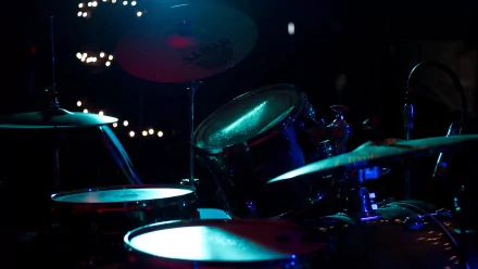 A dynamic close-up of a Yamaha drum set featuring a snare and Sabian cymbal, illuminated by blue lighting, capturing the essence of percussion music at a concert.