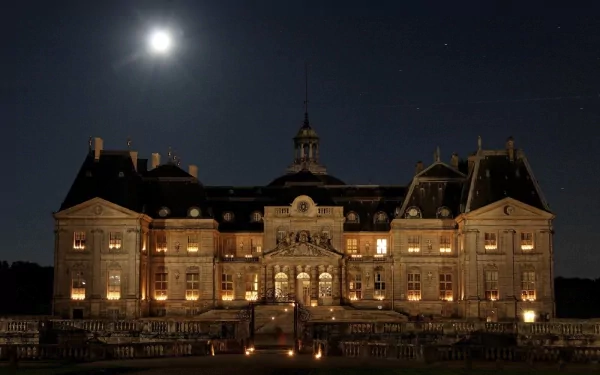 Night view of the illuminated Château de Vaux-le-Vicomte, showcasing its grand architecture under the moonlight in a HD PC desktop wallpaper and background.