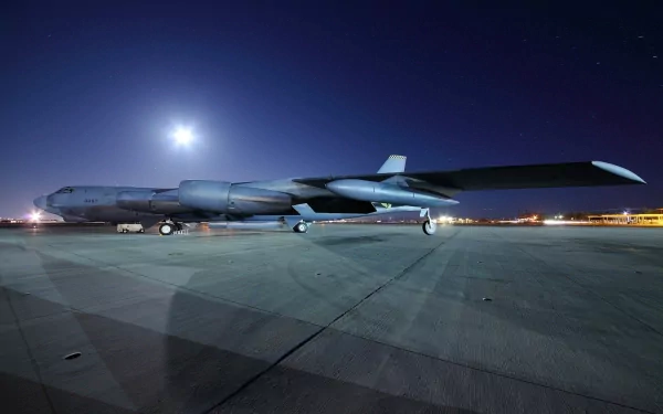 A Boeing B-52 Stratofortress parked on an airfield under a moonlit sky, showcasing its iconic profile. This HD image serves as a striking desktop wallpaper.