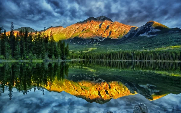 HD nature desktop wallpaper showing vibrant mountain peaks mirrored perfectly in a calm lake under a dramatic cloudy sky.