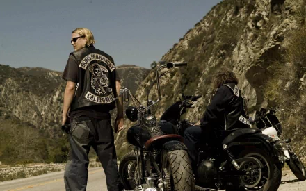 A scene from the TV show Sons of Anarchy, featuring two bikers on the road, with rugged mountains in the background, embodying the show's themes of rebellion and camaraderie.