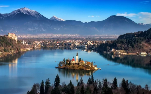 Scenic HD wallpaper of Lake Bled featuring the Assumption of Mary Church on the island, surrounded by calm waters and mountains under a clear blue sky.