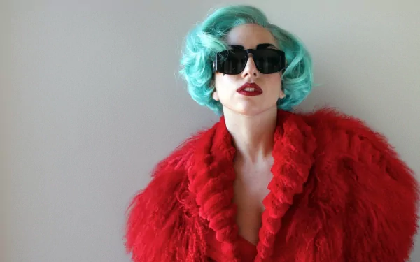 HD desktop wallpaper of American singer Lady Gaga with blue hair, red lipstick, oversized sunglasses, and a vibrant red fur coat against a plain background.