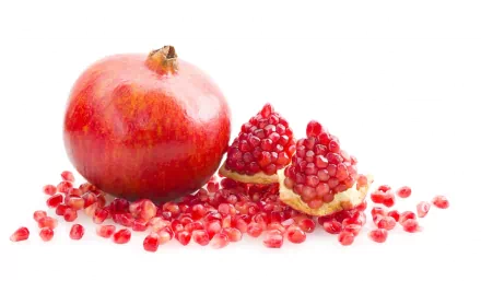 HD PC desktop wallpaper featuring a vibrant whole pomegranate and its scattered seeds on a clean white background.