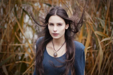 A beautiful woman with long dark hair standing amidst autumnal foliage, captured in sharp detail for a 4K Ultra HD PC desktop wallpaper.