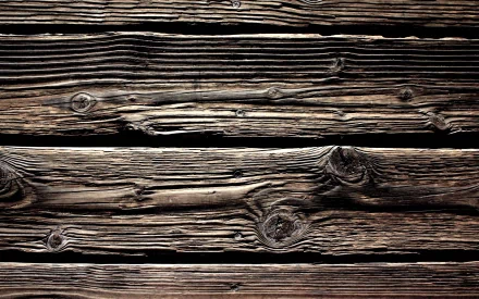 Artistic HD wallpaper featuring rich textures of dark, weathered wood planks, showcasing unique knots and grain patterns for a rustic and warm background.