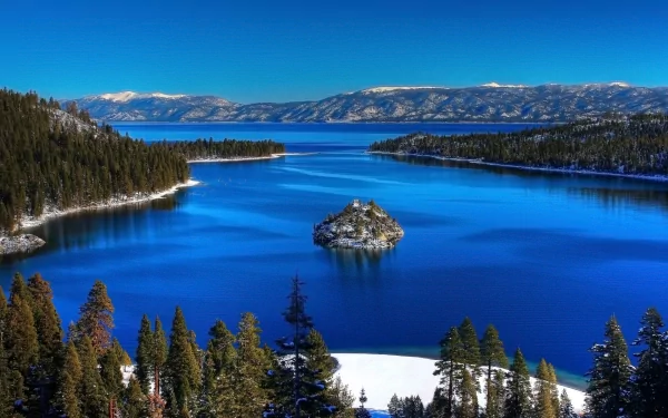 HD PC desktop wallpaper featuring the vibrant blue waters of Lake Tahoe surrounded by forested shores and snow-capped mountains under a clear sky.