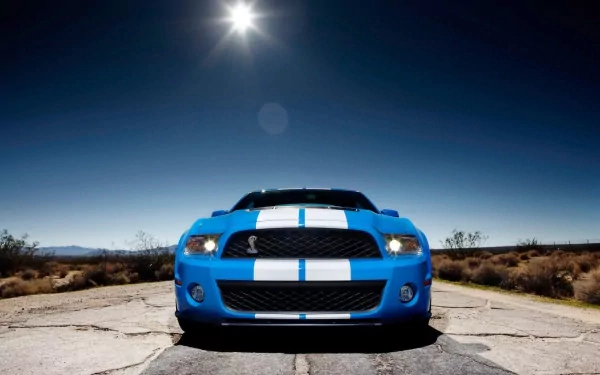 HD desktop wallpaper featuring a blue Ford Mustang Shelby GT500 with white racing stripes, set against a clear sky and desert landscape.