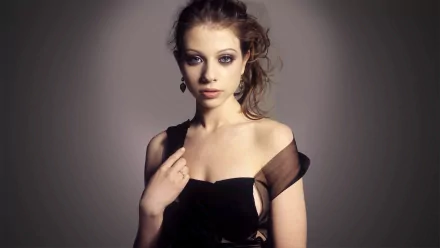 A striking HD wallpaper featuring celebrity Michelle Trachtenberg, showcasing her elegant pose and captivating expression in a stylish black dress.