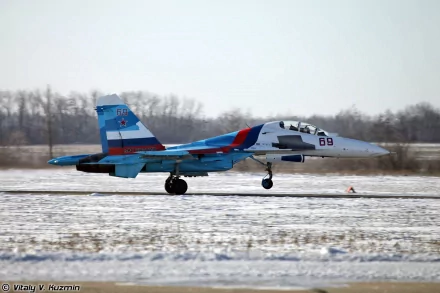 HD desktop wallpaper of a military Sukhoi Su-30 aircraft on a snowy runway, with a clear sky and trees in the background.