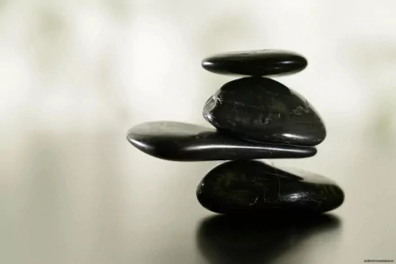 HD nature-themed PC desktop wallpaper featuring a balanced stack of smooth black stones against a soft, blurred background.