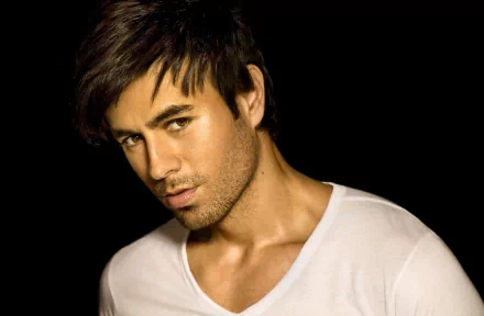 HD desktop wallpaper featuring Enrique Iglesias with a confident expression, set against a dark background, emphasizing his music career.