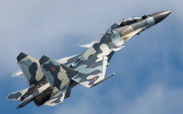 A high-definition desktop wallpaper featuring a Sukhoi Su-30 military aircraft in flight with a camo paint scheme against a cloudy sky backdrop.