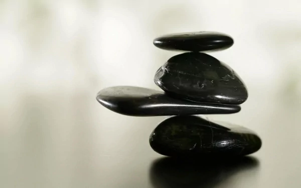 HD nature-themed PC desktop wallpaper featuring a balanced stack of smooth black stones against a soft, blurred background.
