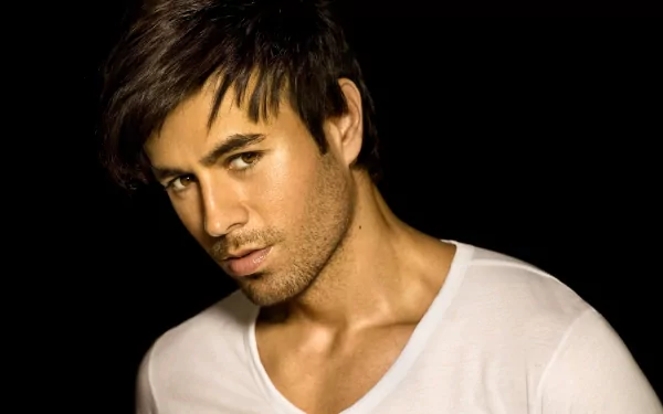HD desktop wallpaper featuring Enrique Iglesias with a confident expression, set against a dark background, emphasizing his music career.