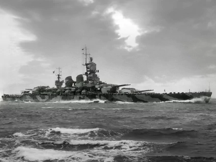 Black and white HD desktop wallpaper featuring a large military battleship sailing through choppy waters under a cloudy sky.