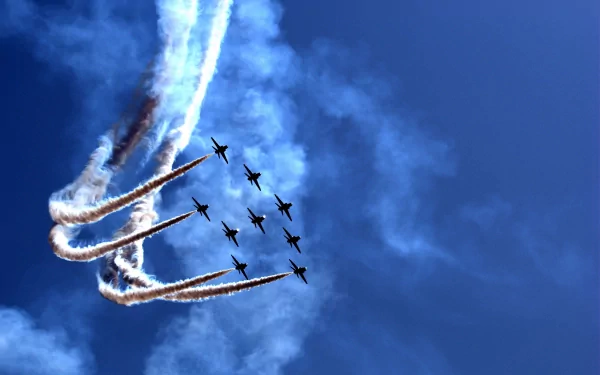 5K Ultra HD PC desktop wallpaper showing aircraft (vehicles) in a tight aerobatic formation leaving swirling smoke trails against a vivid blue sky.