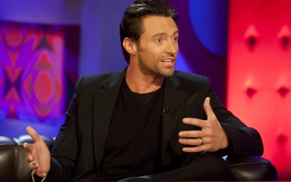 Hugh Jackman engages in conversation, showcasing his charismatic presence in this HD PC desktop wallpaper, featuring a vibrant backdrop that highlights his dynamic expression.