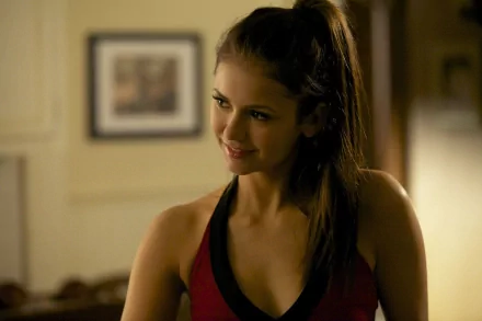 HD wallpaper featuring Nina Dobrev smiling playfully in a red outfit, with a warm and inviting background. A vibrant desktop background for fans of the celebrity.