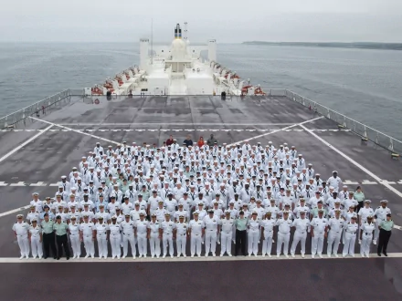 USNS Comfort (T-AH-20) crew in white uniforms assembled on the flight deck of the military hospital ship/warship, shown as a 2K Quad HD desktop wallpaper.