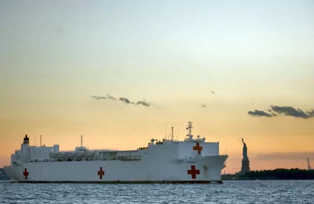 USNS Comfort (T-AH-20) hospital ship with red crosses at sunset near the Statue of Liberty — military warship 2K Quad HD PC desktop wallpaper