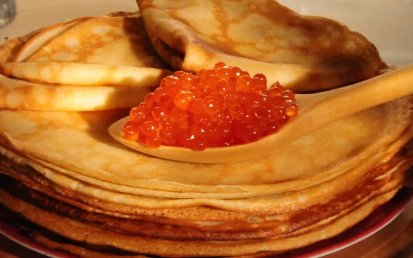 2K Quad HD PC desktop wallpaper: stack of golden crêpes on a plate with a spoonful of bright orange salmon caviar on top, close-up food background.
