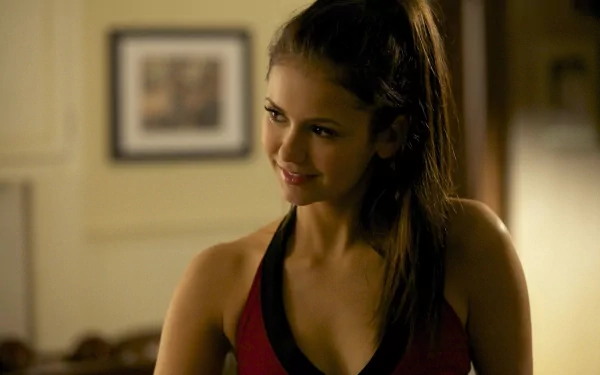 HD wallpaper featuring Nina Dobrev smiling playfully in a red outfit, with a warm and inviting background. A vibrant desktop background for fans of the celebrity.