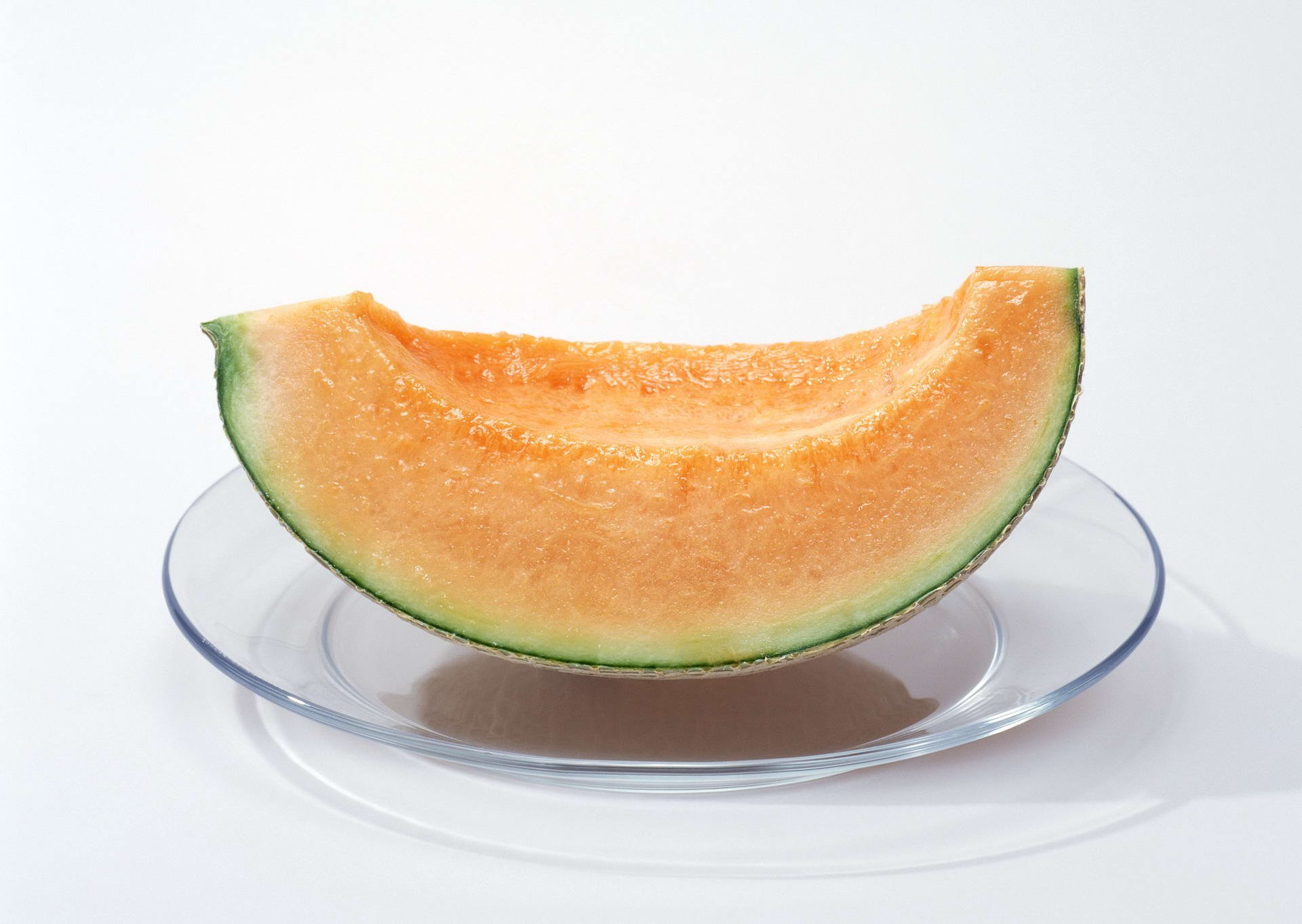 HD PC desktop wallpaper featuring a close-up of a fresh cantaloupe melon slice on a clear plate against a white background.