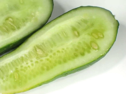 HD PC desktop wallpaper/background: close-up of a halved cucumber (food) on a white background, vibrant green flesh and seeds visible.