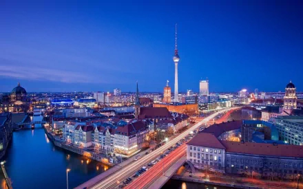 A stunning HD wallpaper of Berlin at dusk, showcasing the city’s skyline with the iconic TV Tower and vibrant lights along the Spree River and historic architecture.