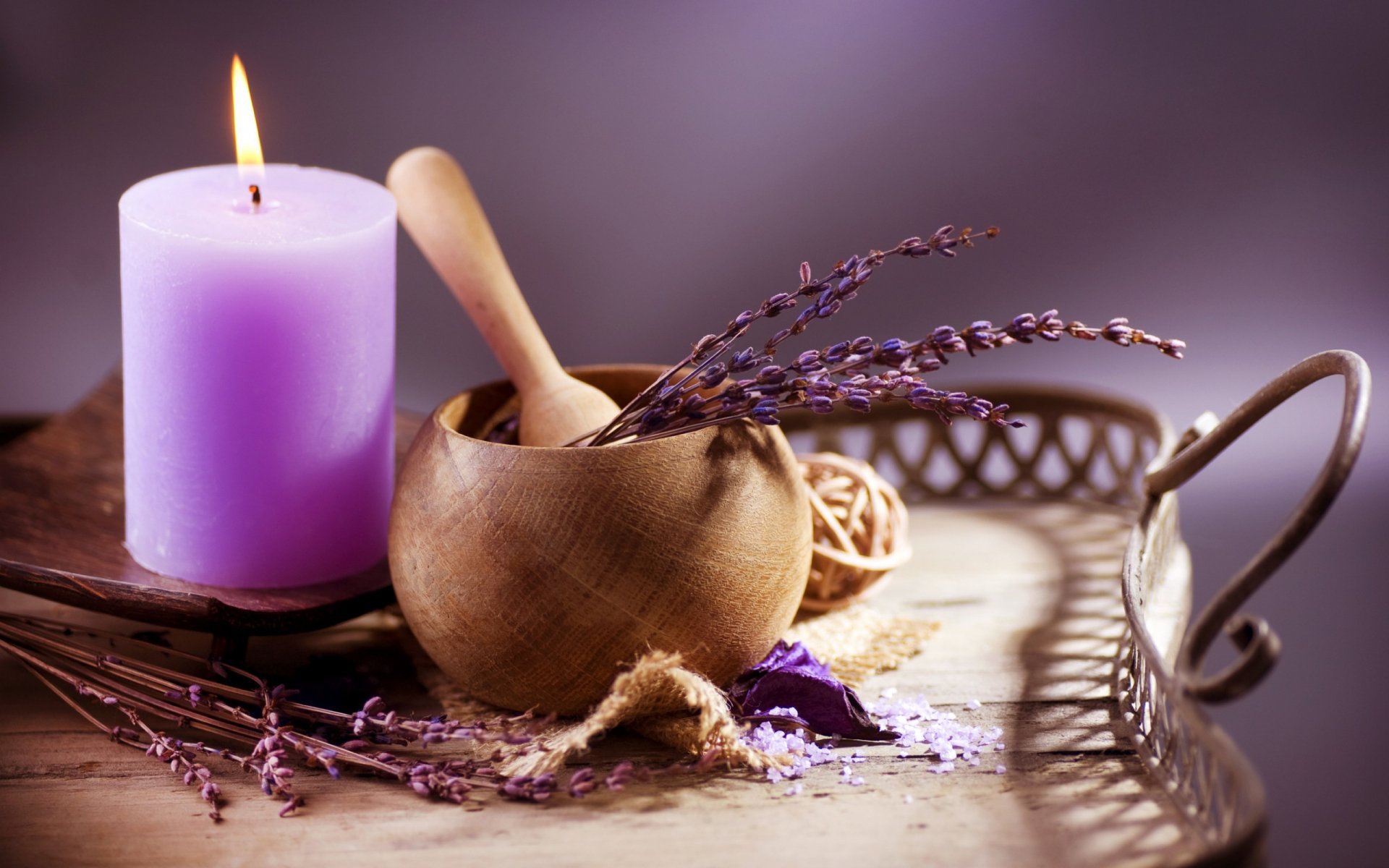 HD PC desktop wallpaper featuring a man-made spa scene with a lit lavender candle, dried lavender sprigs, and a wooden mortar and pestle on a decorative tray.