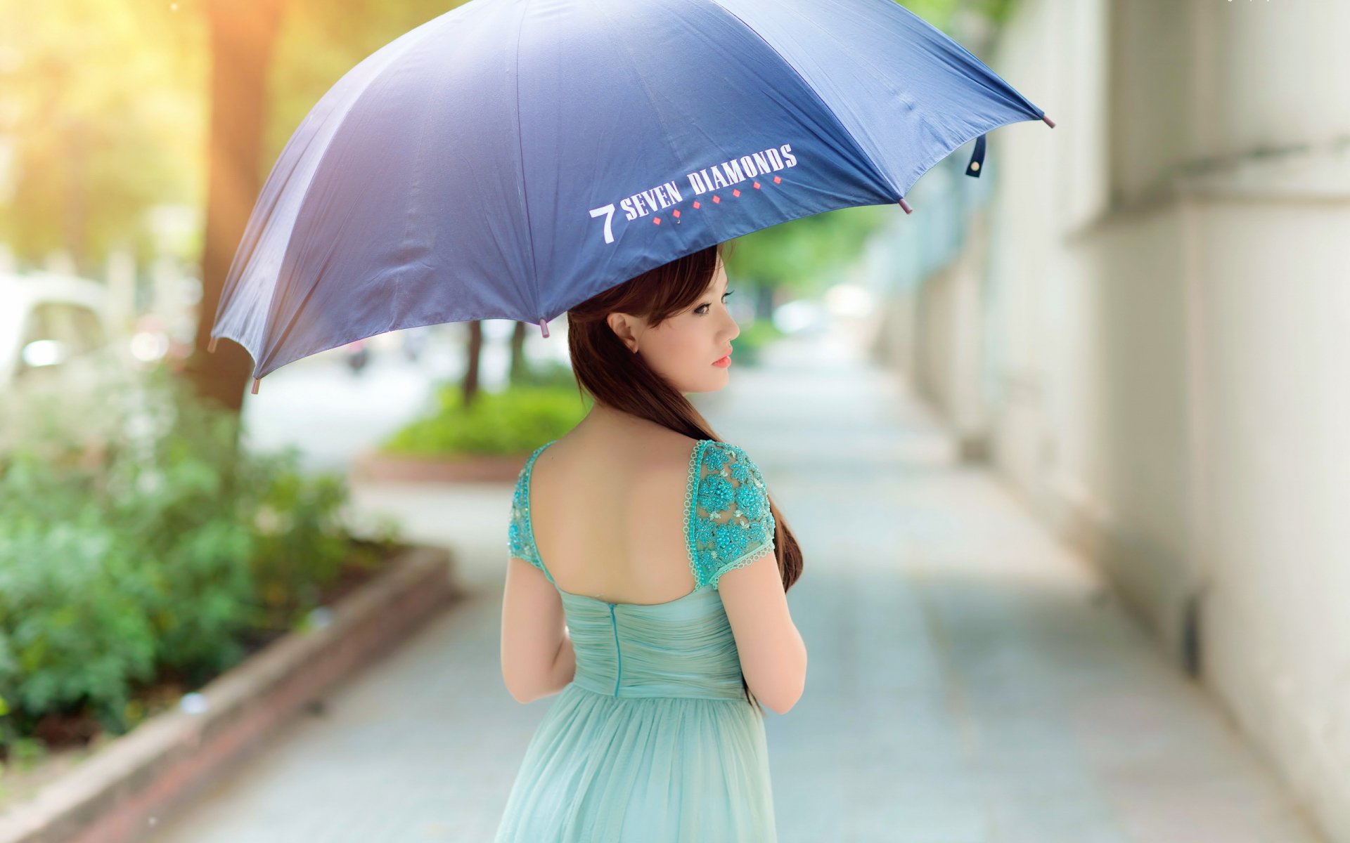 HD desktop wallpaper featuring an Asian woman holding a blue umbrella, wearing a light blue dress, walking along a sunlit sidewalk. The text 7 Seven Diamonds is visible on the umbrella.