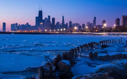 Chicago skyline at twilight over a frozen lakeshore, illuminated man-made buildings against a deep blue sky — HD PC desktop wallpaper background.