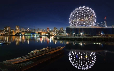 Vancouver's stunning skyline at night, featuring a glowing dome structure reflecting in the water, captures the beauty of Canada's vibrant cityscape.