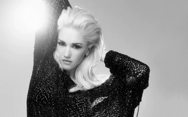 Black and white HD desktop wallpaper featuring Gwen Stefani posing with her arm raised, showcasing her platinum blonde hair and textured black outfit.