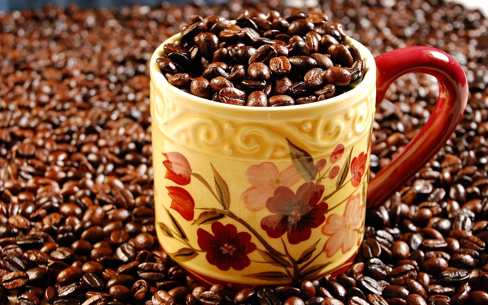 HD PC desktop wallpaper featuring a decorative yellow and red mug filled with coffee beans, surrounded by more coffee beans scattered around.
