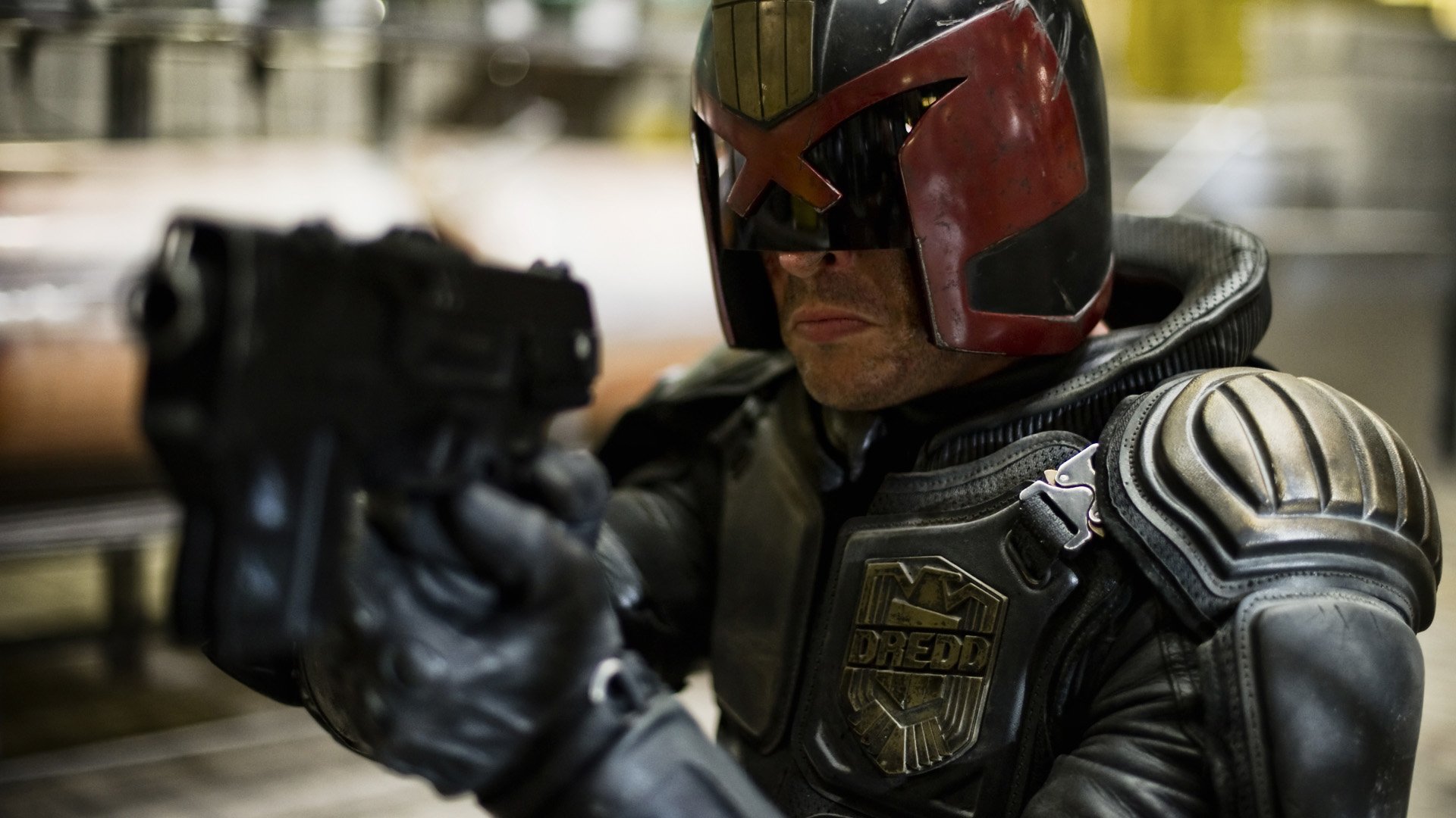 HD PC desktop wallpaper featuring Judge Dredd from the Dredd movie, showcasing the character in detailed armor aiming a firearm.
