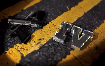 HD PC desktop wallpaper featuring a handgun, bullet, and metallic IV emblem on asphalt, representing the video game Grand Theft Auto IV.