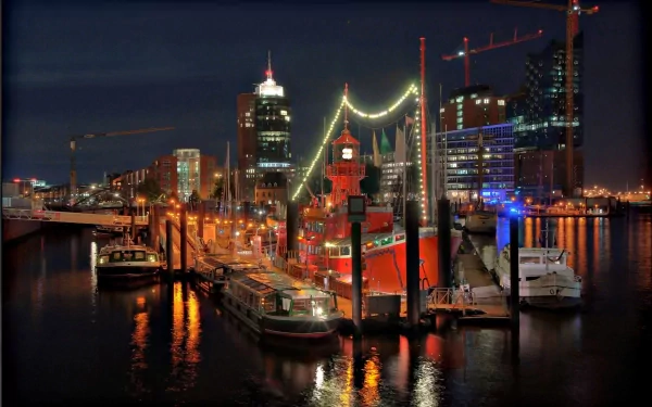 Nighttime view of Hamburg's harbor with illuminated ships and city skyline, showcasing man-made structures reflected in calm water, captured in HD for desktop wallpaper.