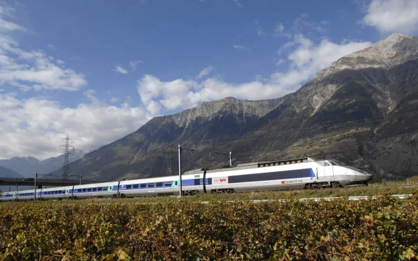 HD desktop wallpaper featuring a sleek high-speed train traveling through a scenic mountainous landscape under a partly cloudy sky.