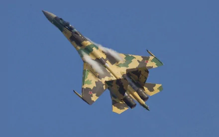 A Sukhoi Su-35 warplane performs a steep climb against a clear blue sky, showcasing its striking camouflage design in this high-definition military aircraft wallpaper.